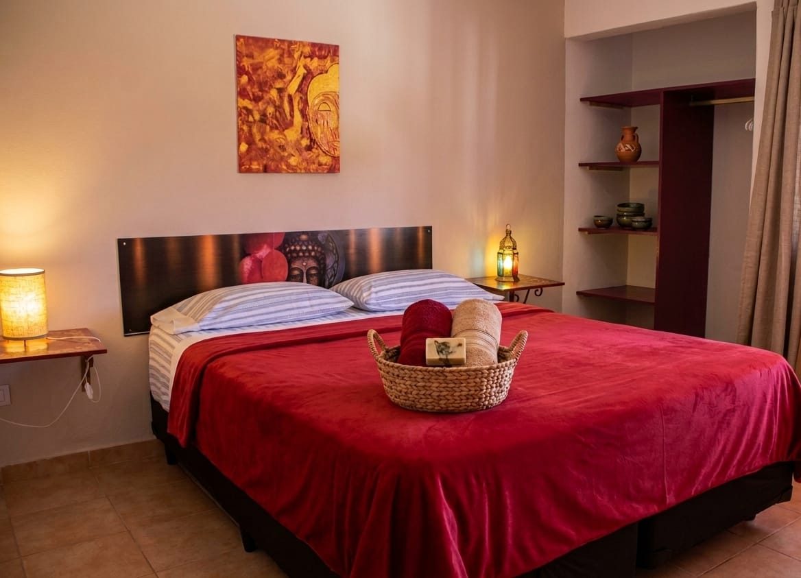 Dormitorio con cama queen size y colcha roja
